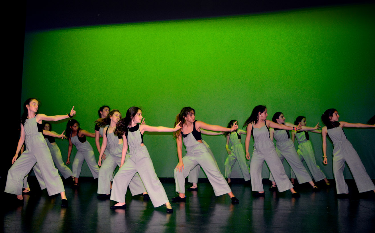 chicas del grupo 3baile con el fondo verde y peto gris con el brazo extendido